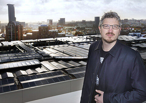 Portretfoto Arjan Kapteijns geheel in het zwart gekleed. Genomen vanaf een dak.