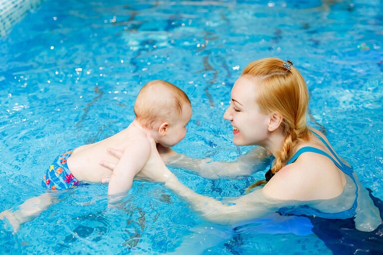 Lachende moeder en baby in het zwembad