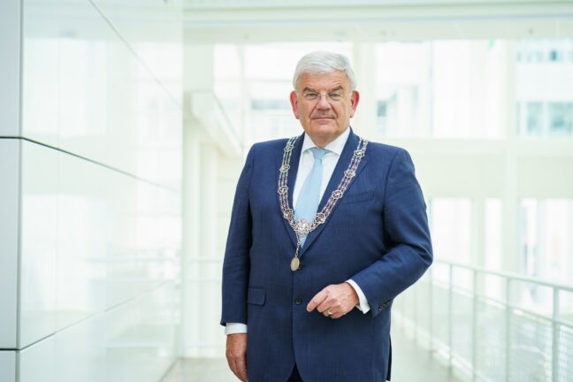 Portretfoto Jan van Zanen in donkerblauw pak en met de ambtsketting om.