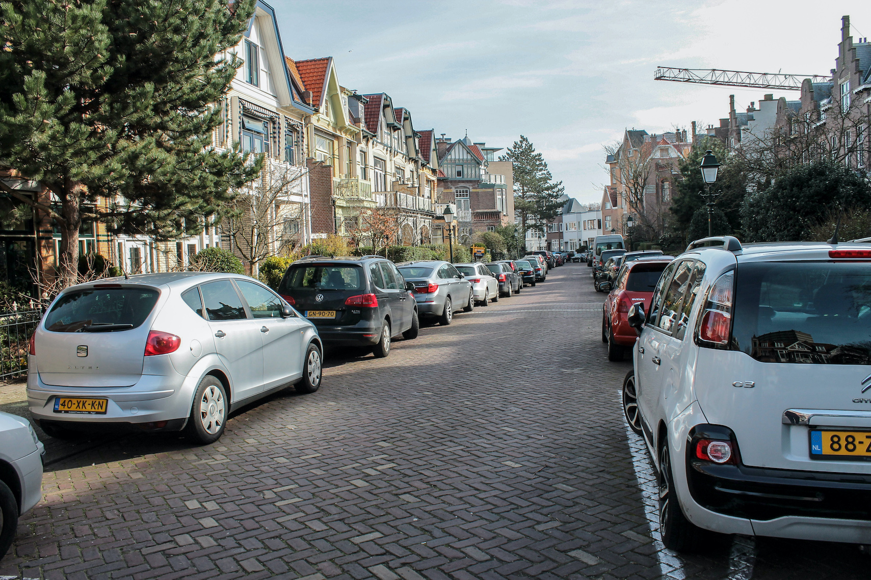 Straat met huizen aan weerszijden en parkeervakken links en rechts vol.