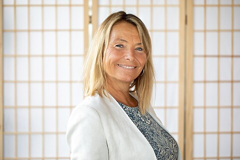 Julie, vrouw met brede lach, blond haar, wit jasje