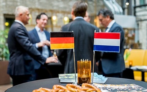 CLose up van twee vlaagen op een borreltafel: 1 met Duitse en 1 met Nederlandse vlag.