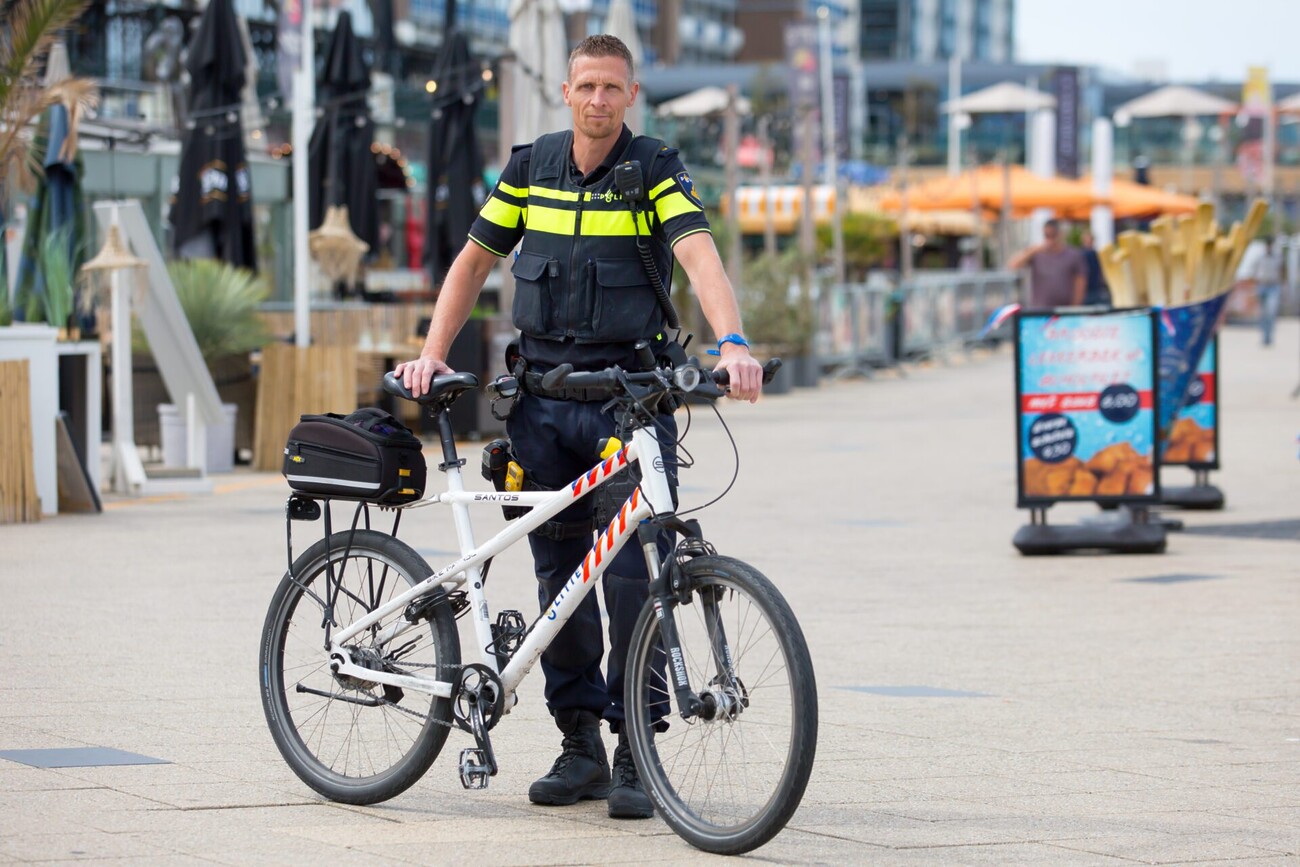 Wijkagent Peter poseert met fiets voor horeca