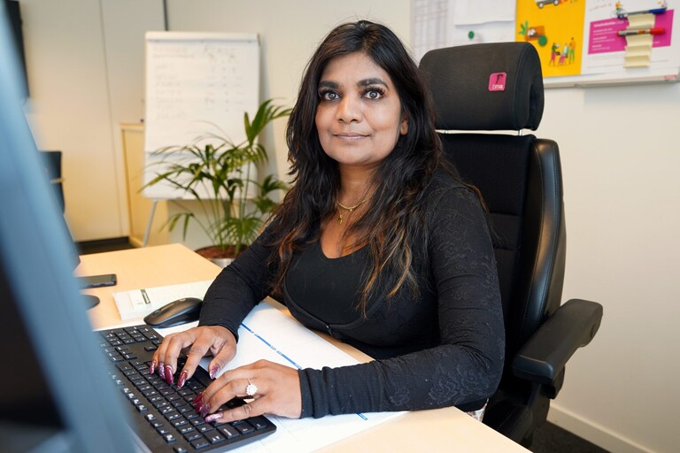 Sandra achter haar bureau, de handen op haar keyboard.