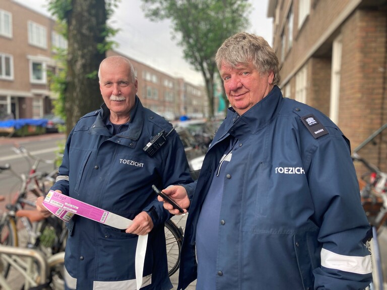 Toezichthouders Bert en Karel in hun grijs-blauwe uniform op straat
