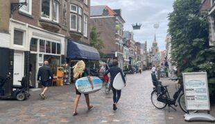 2 jonge surfers met plank lopen door de Keizerstraat