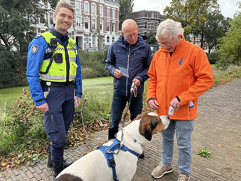 Handhaver, 2 bewoners en hond op straat tijdens de wijkactie Kak in de Bak in Duinoord