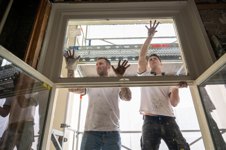 2 mannen vervangen het glas van ramen in een monumentaal pand