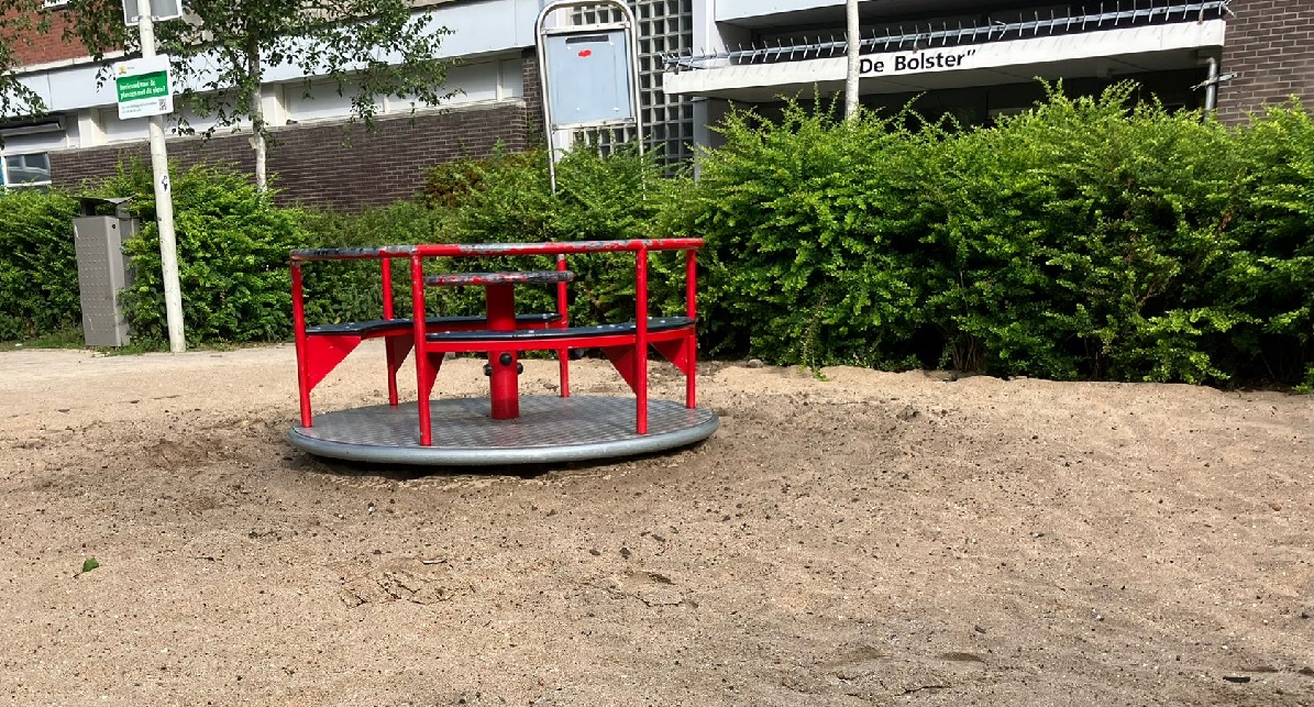 Speeltoestel. Het speeltoestel is gemaakt om op te zitten en rond te draaien. Het heeft een rode kleur en staat op een stuk zand bij speeltuin Kastanjeplein in de Bomenbuurt.