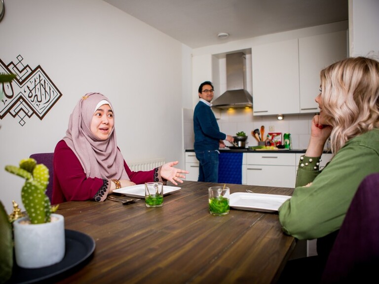 Buren bespreken aan de keukentafel de mogelijkheden om samen hun gebouw te isoleren.