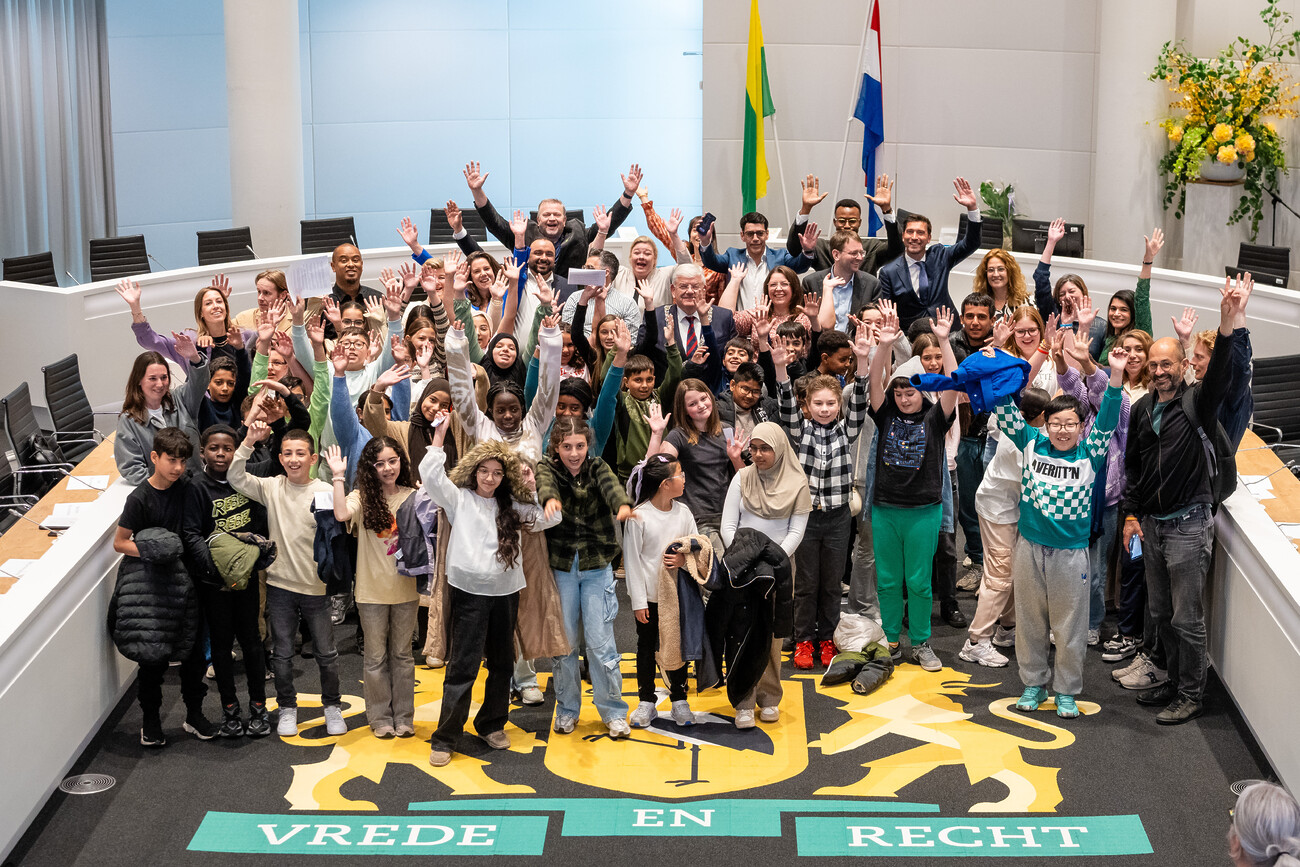 Groepsfoto van alle aanwezige kinderen met de burgemeester en aanwezige politici bij het kindervragenuur.