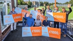 Leden van sportclubs met grote wit-oranje waardechecks met de naam van hun club en het bedrag van 1000 euro.