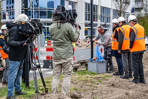 Hijsen vlaggen van NATO en de NAVO-top vlaggenparade op de Johan de Wittlaan. Twee cameramannen filmen medewerkers die de vlag hijsen.