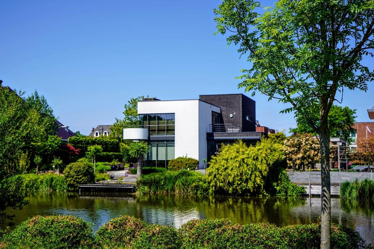 Een villa in Vroondaal met witte en zwarte gevel. Gelegen aan het water. Veel groen rondom in de omgeving.
