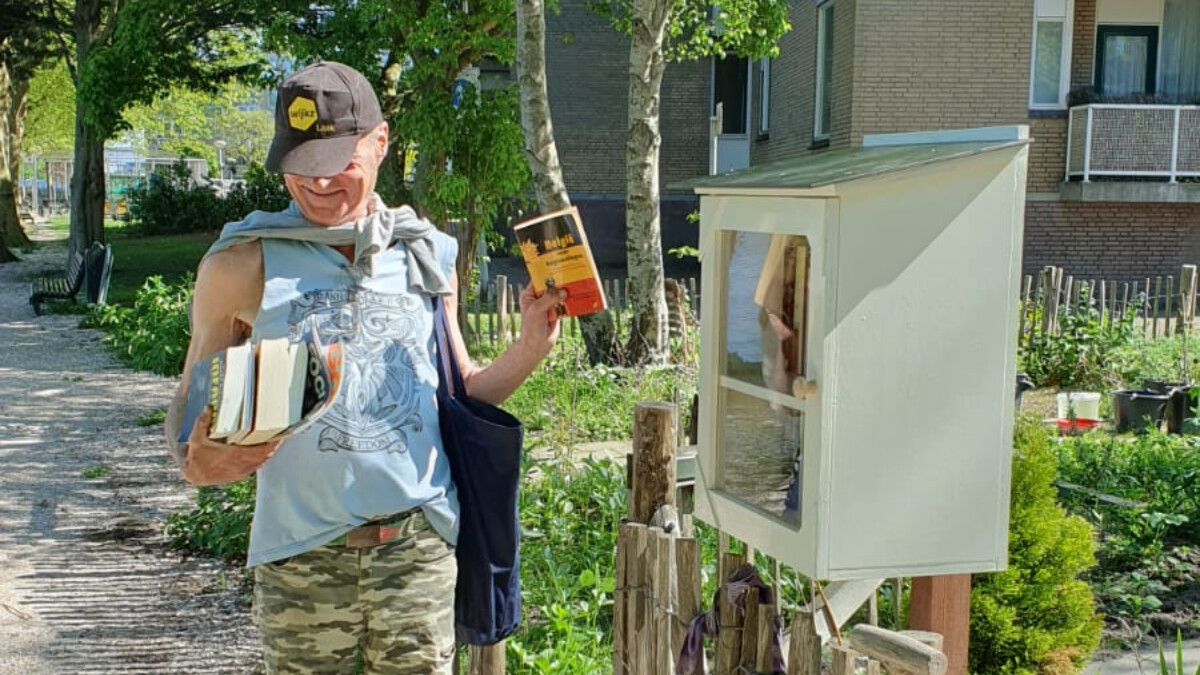 Jan-Willem bij de MiniBieb aan de Bontekoekade. Hij houdt verschillende boeken in zijn handen.