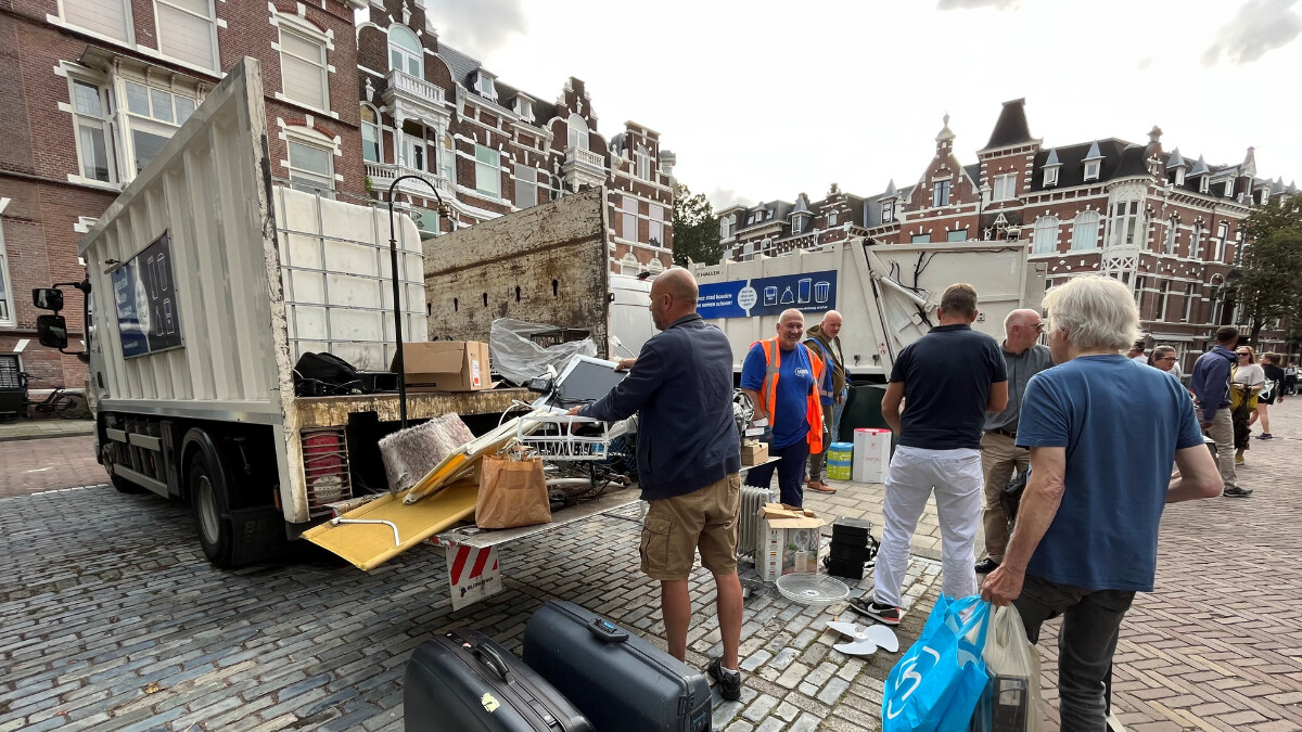 Mensen gooien oude spullen in een vrachtwagen.