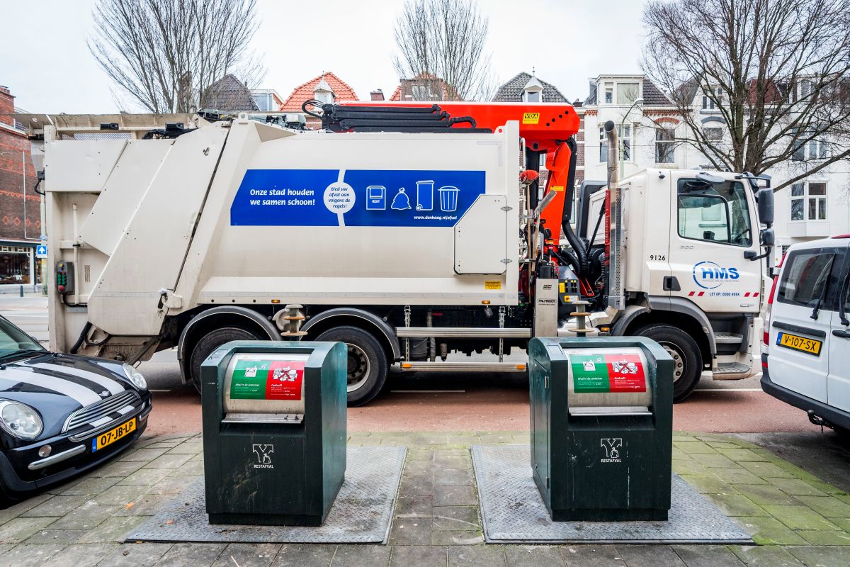 Vuilnisophaalwagen van HMS met op de voorgrond 2 ondergrondse restafvalcontainers