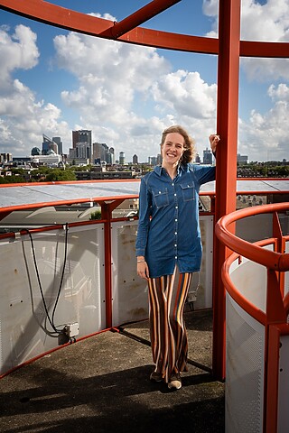 Een vrouw leunt tegen een rode paal.