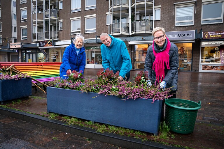 3 vrijwilligers lachend op de foot. Ze zijn bezig met de beplantingsvakken op het Loosduinse Hoofdplein.