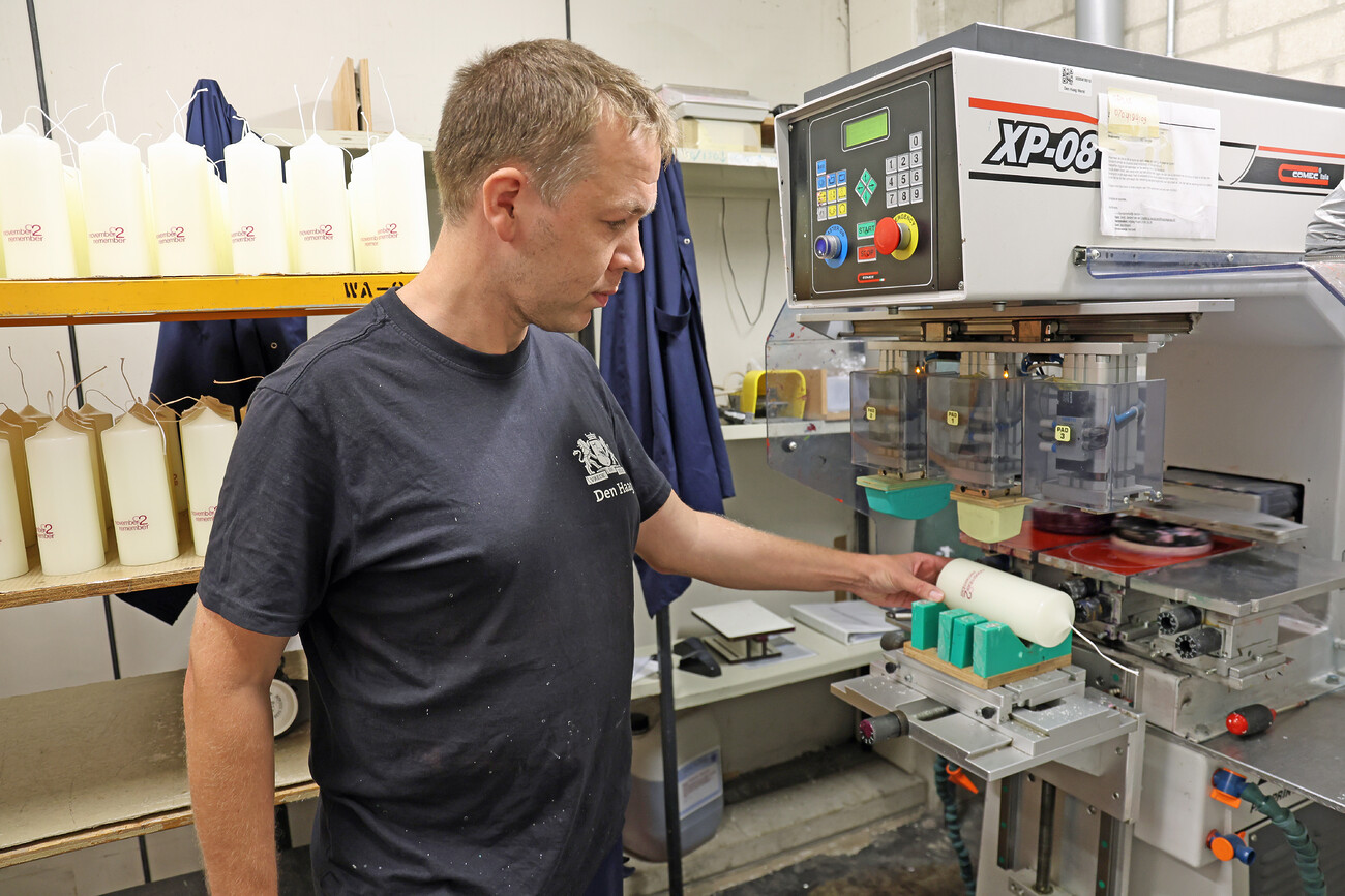 Een medewerker van Den Haag Werkt plaatst tekst op een kaars.