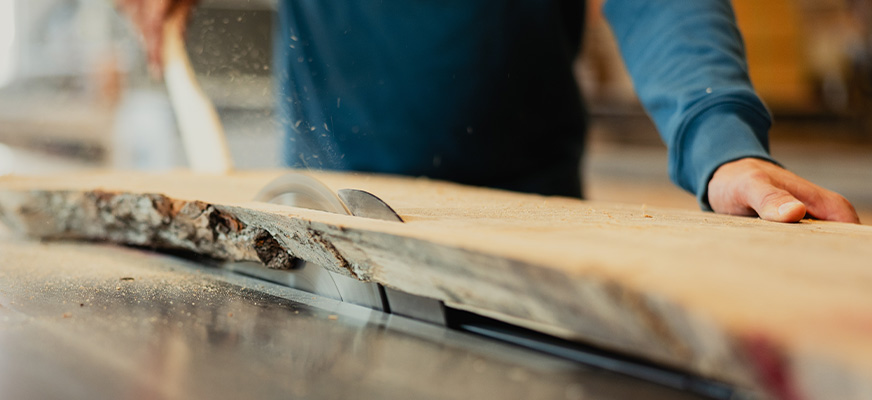 Close-up van een houten plank die wordt gezaagd op een zaagmachine