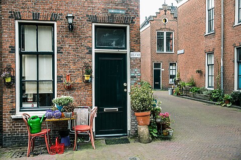 Huis met 2 huisnummers en tafel en 2 stoelen voor het raam