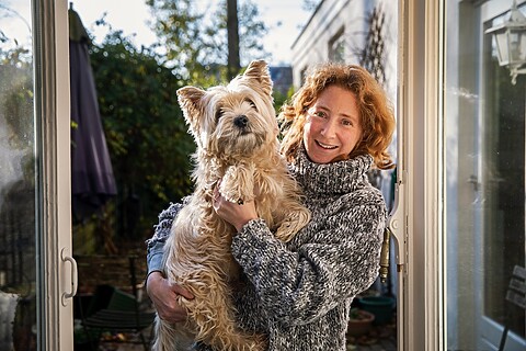 Vrouw staat voor huis met hond in de armen