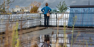 Vrouw kijkt vanaf het dak van de Energiekas Helena uit op de stad.