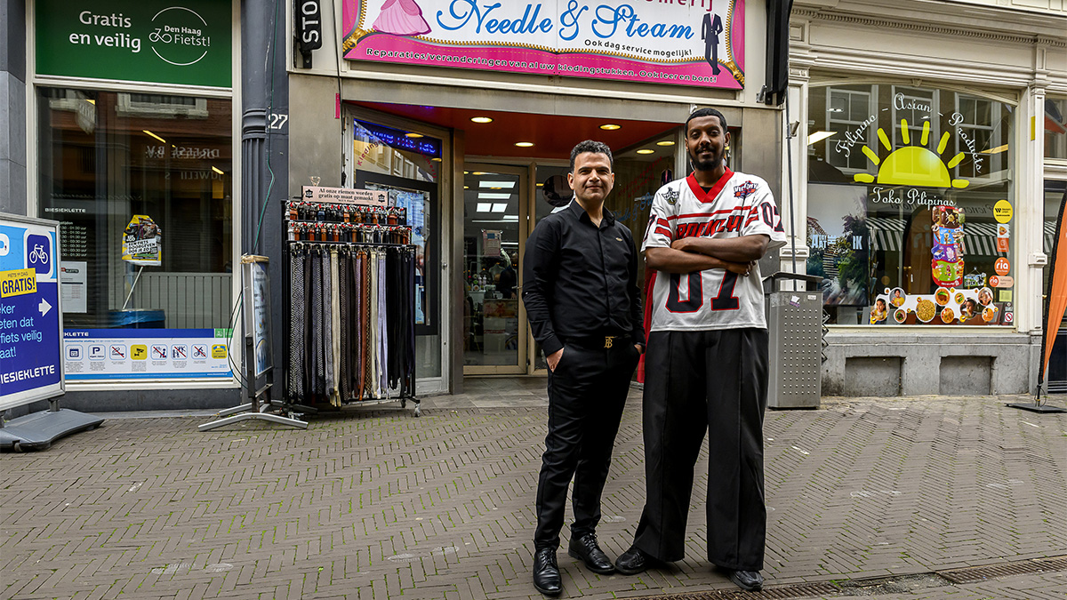 Medewerker Anas en eigenaar Basir staan voor kledingreparatiezaak Needle and Steam in Den Haag.
