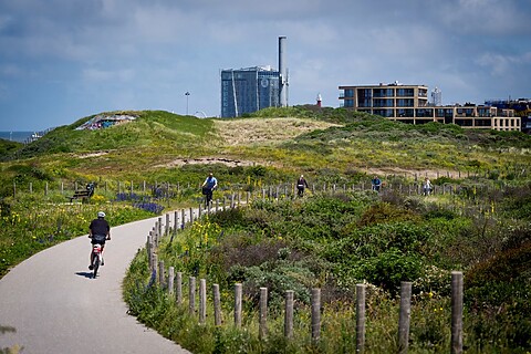 Iemand loopt op een pad tussen de duinen