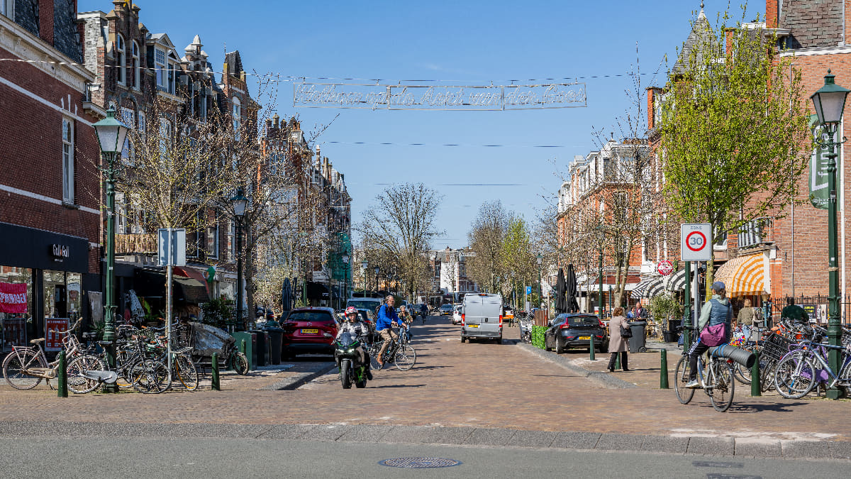 Frederik Hendriklaan met winkels, fietsers, terrassen en bomen langs de straat.