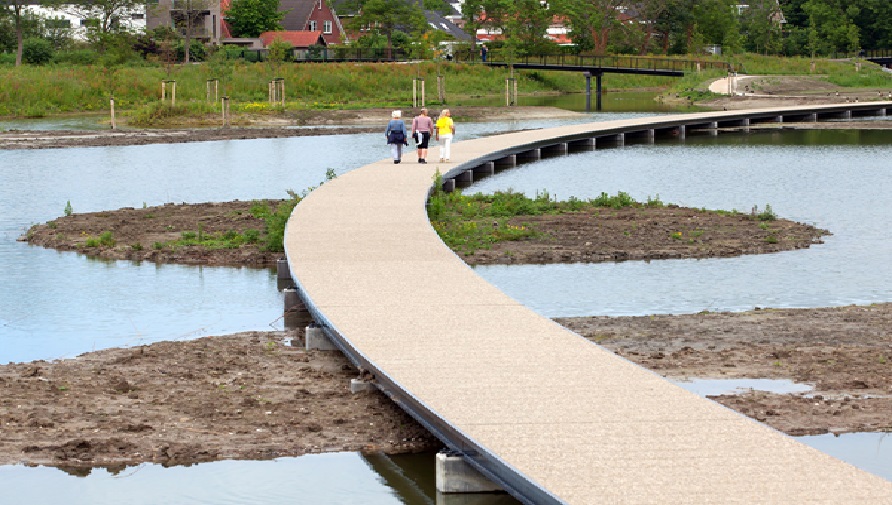 3 people walking on boardwalk above the water