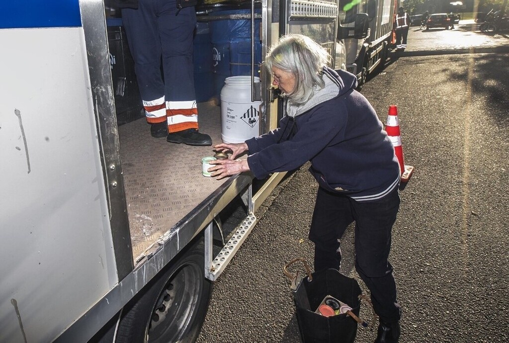 Woman turning in old items by a garbage truck